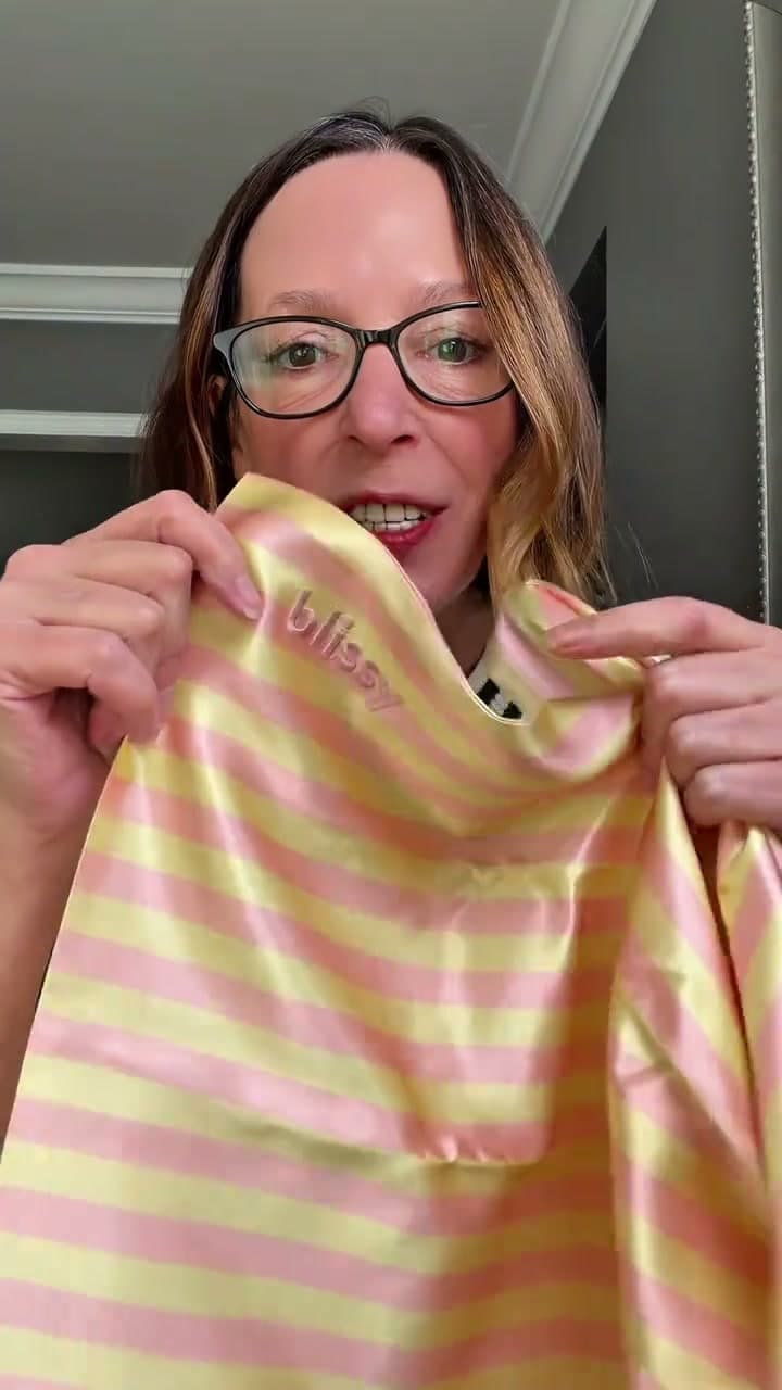 A creator showing the details of a pink and yellow striped Blissy silk pillowcase