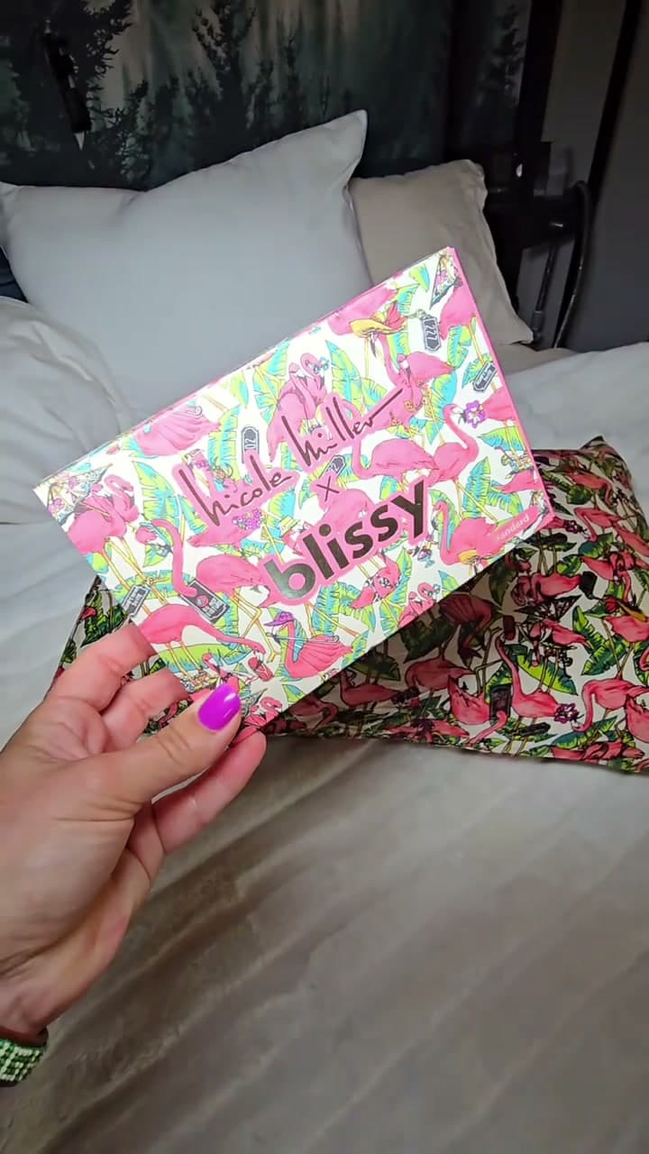 Christy unboxing a colorful Nicole Miller x Blissy pillowcase on her bed